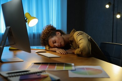 Photo of Tired designer sleeping near computer indoors at night