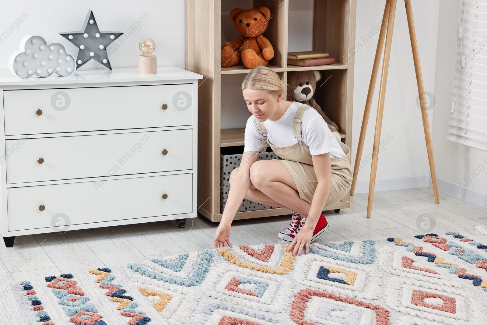 Photo of Female decorator placing carpet in child's room