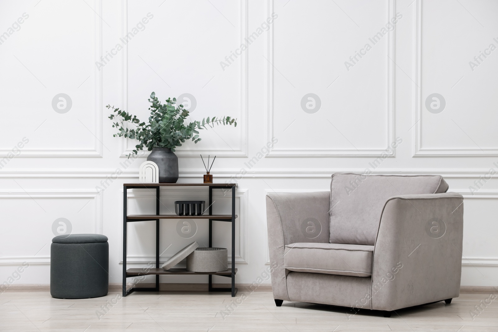 Photo of Console table with decor, pouf and armchair in room. Interior design