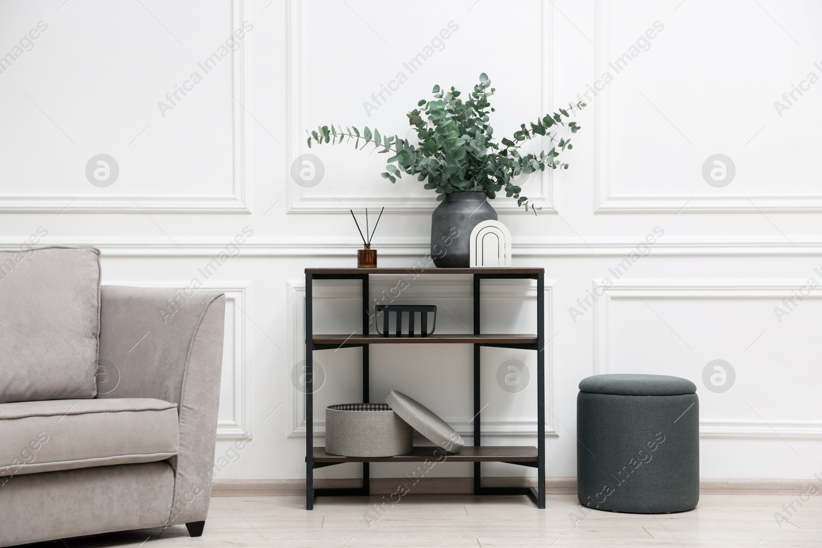 Photo of Console table with decor, pouf and armchair in room. Interior design