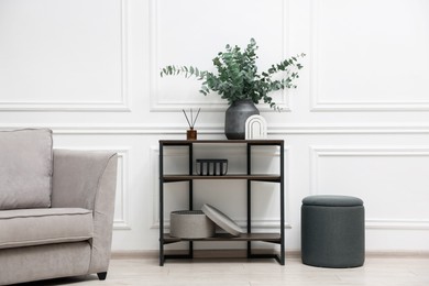 Photo of Console table with decor, pouf and armchair in room. Interior design