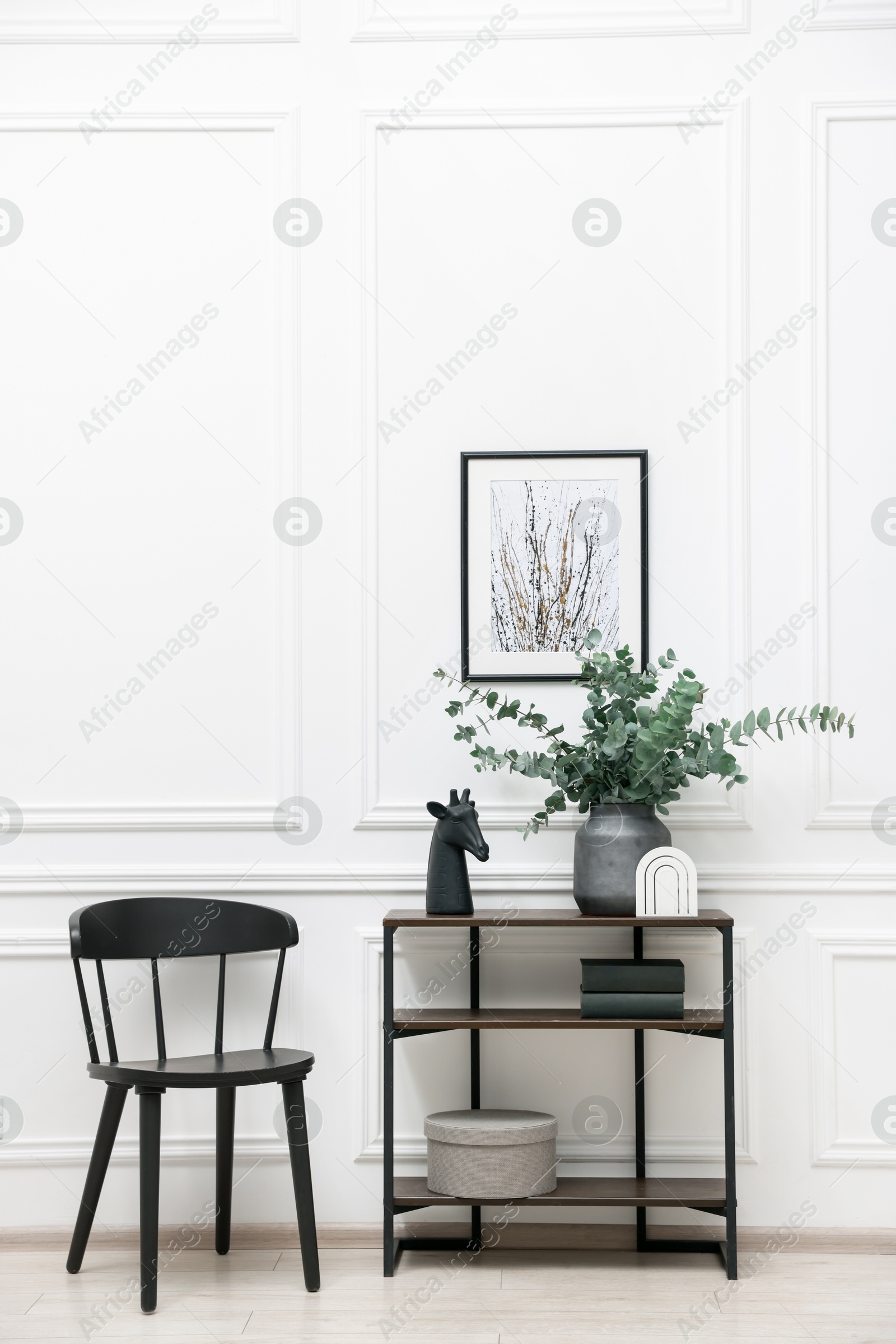 Photo of Console table with decor and chair near white wall in room. Interior design