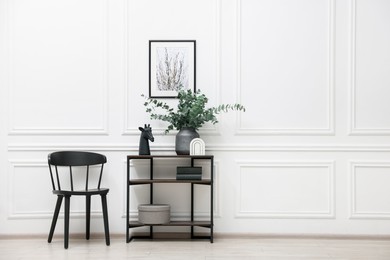 Photo of Console table with decor and chair near white wall in room, space for text. Interior design