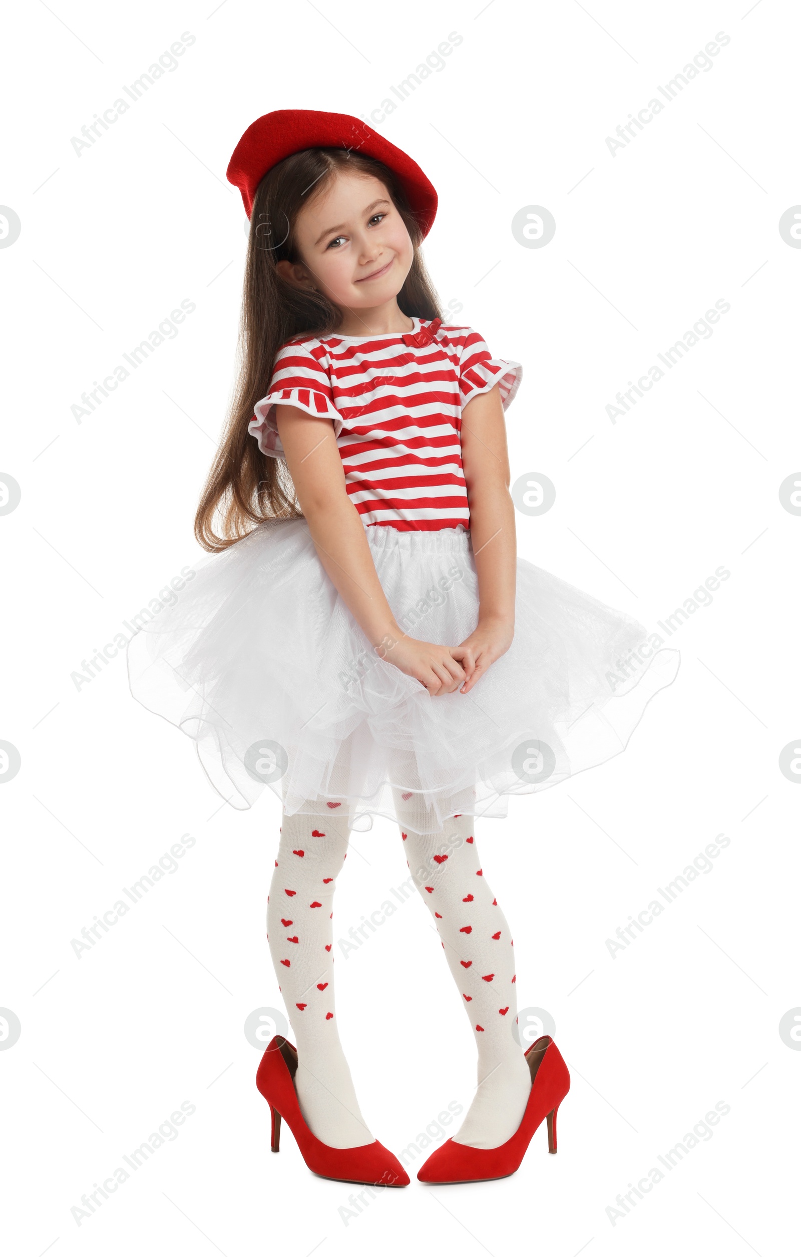 Photo of Stylish little girl wearing oversized high heeled shoes on white background