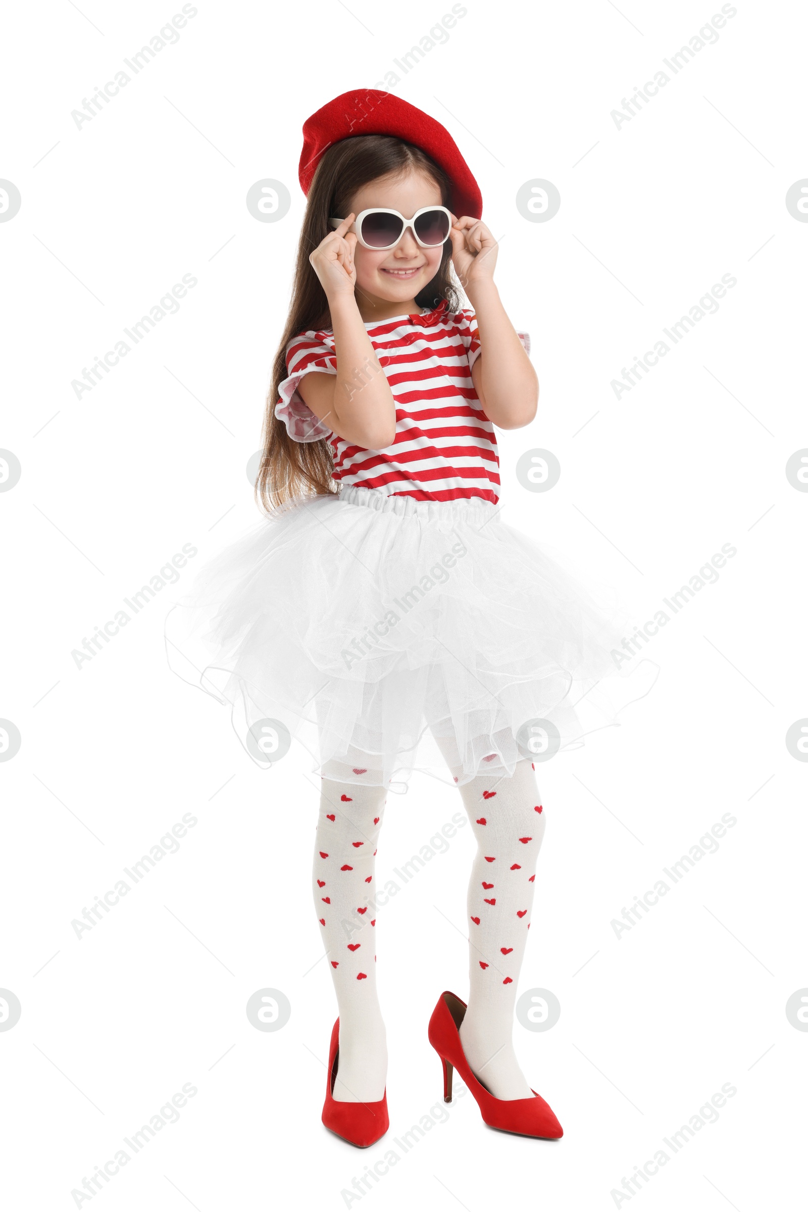 Photo of Stylish little girl wearing oversized high heeled shoes on white background