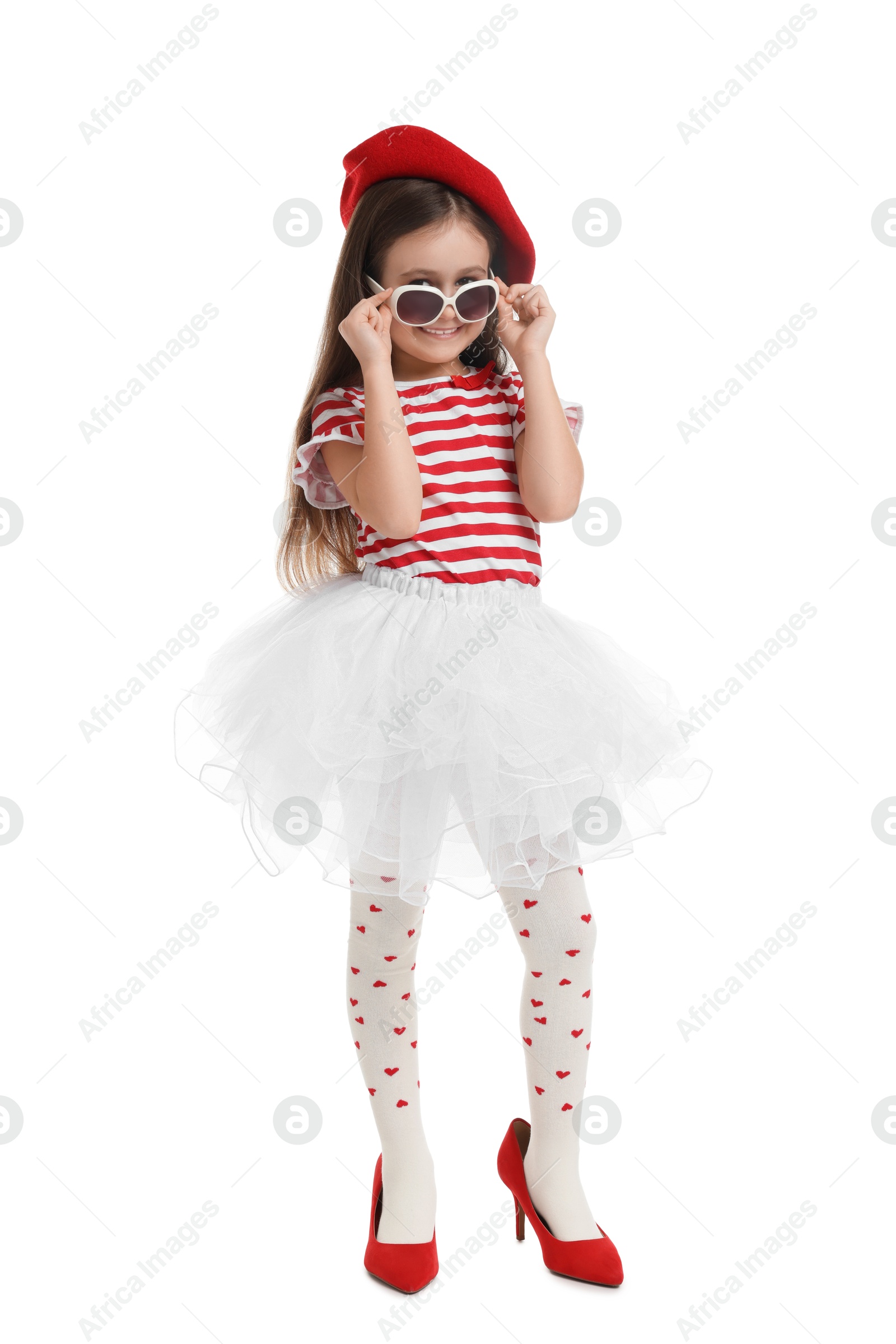 Photo of Stylish little girl wearing oversized high heeled shoes on white background