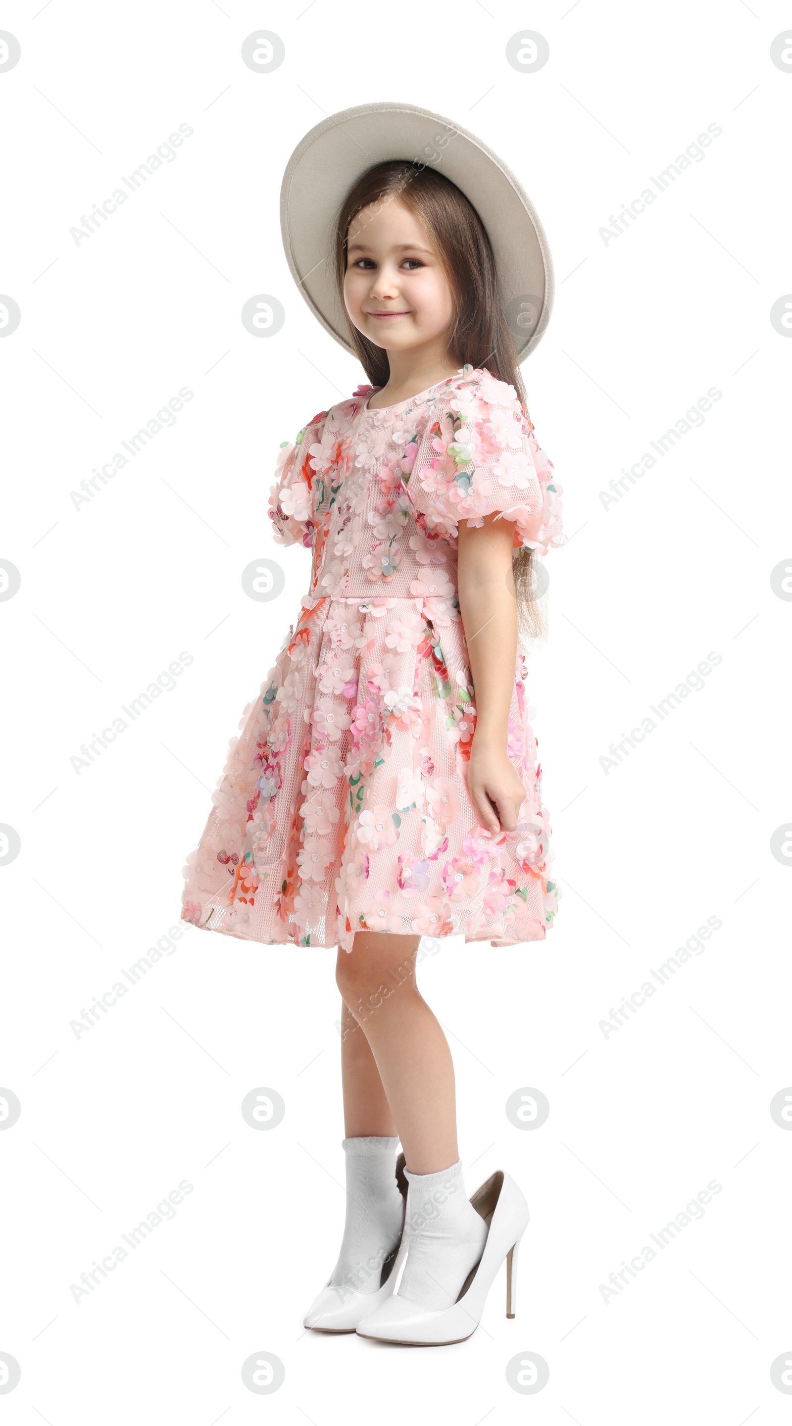 Photo of Stylish little girl wearing oversized high heeled shoes on white background