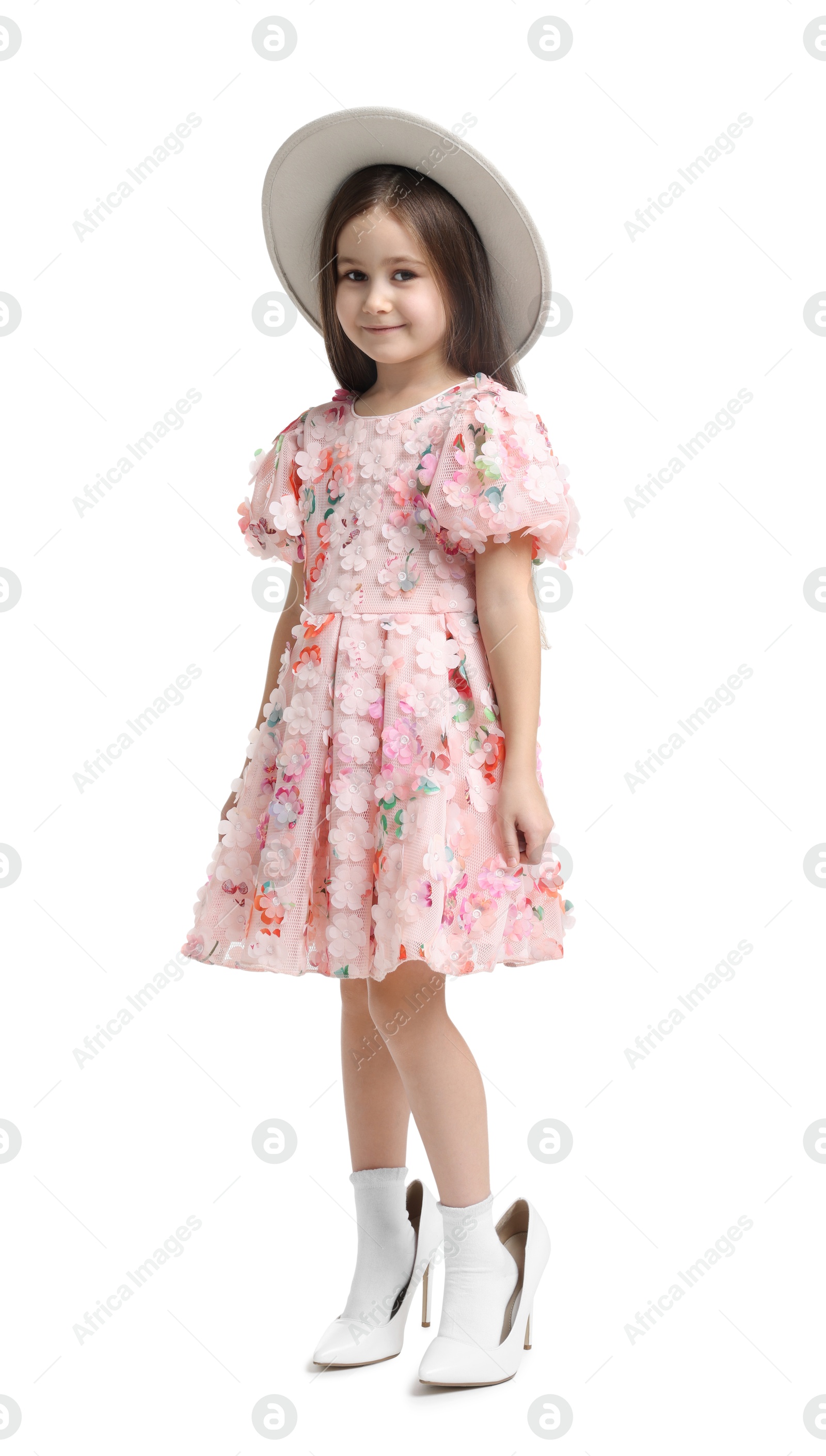 Photo of Stylish little girl wearing oversized high heeled shoes on white background