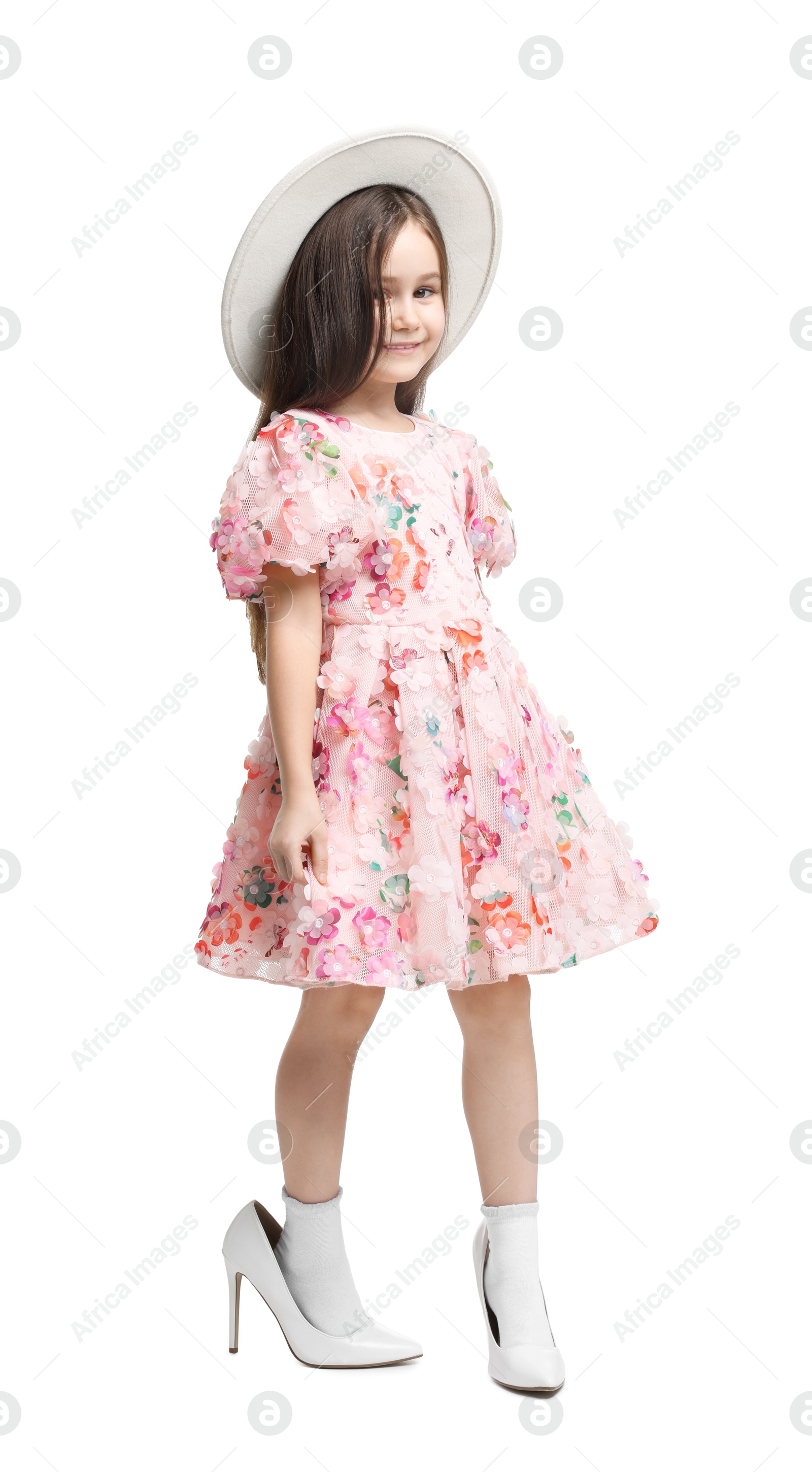 Photo of Stylish little girl wearing oversized high heeled shoes on white background