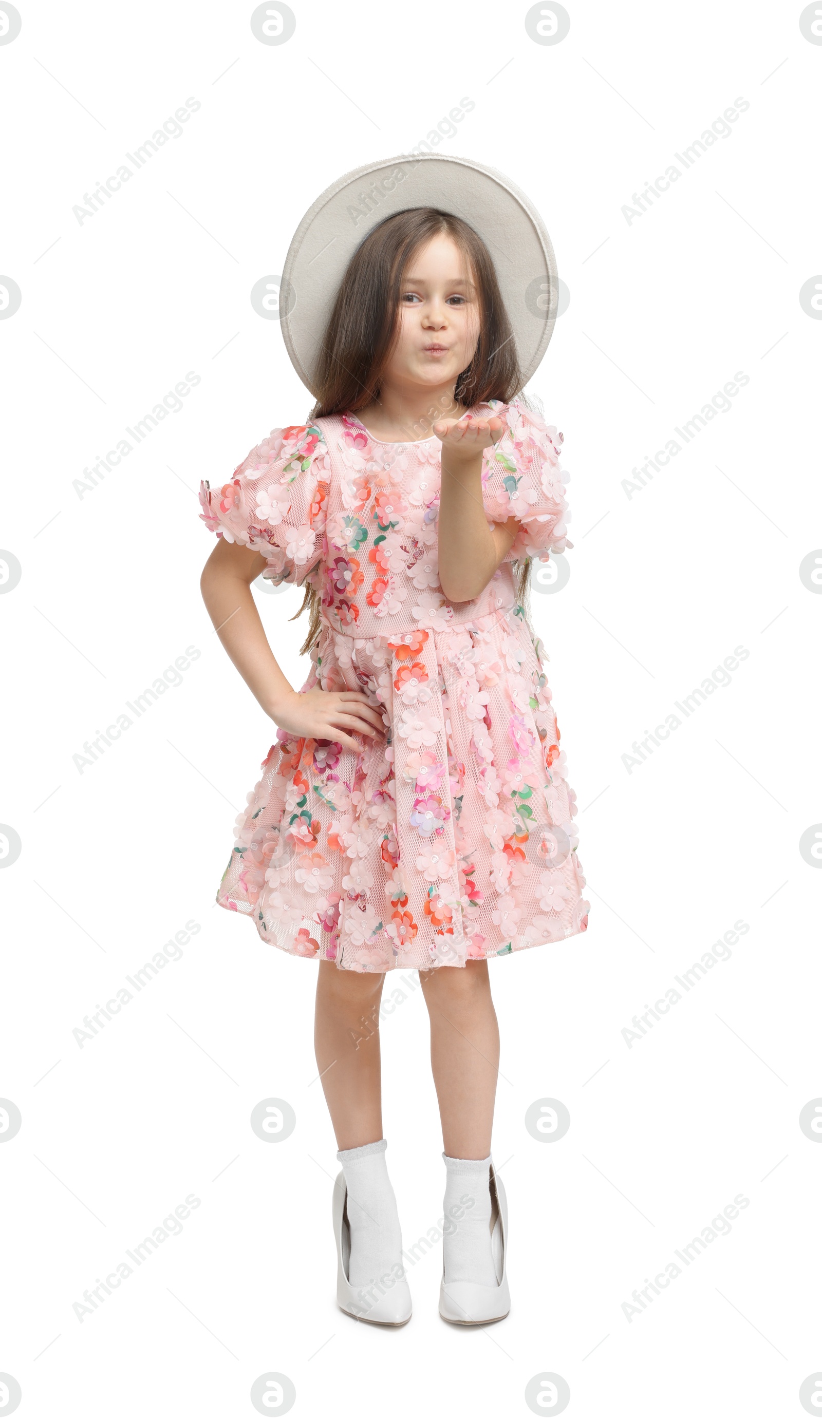 Photo of Stylish little girl wearing oversized high heeled shoes on white background