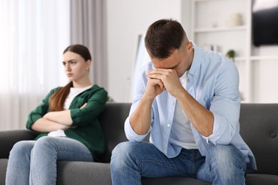 Photo of Offended couple ignoring each other at home, selective focus