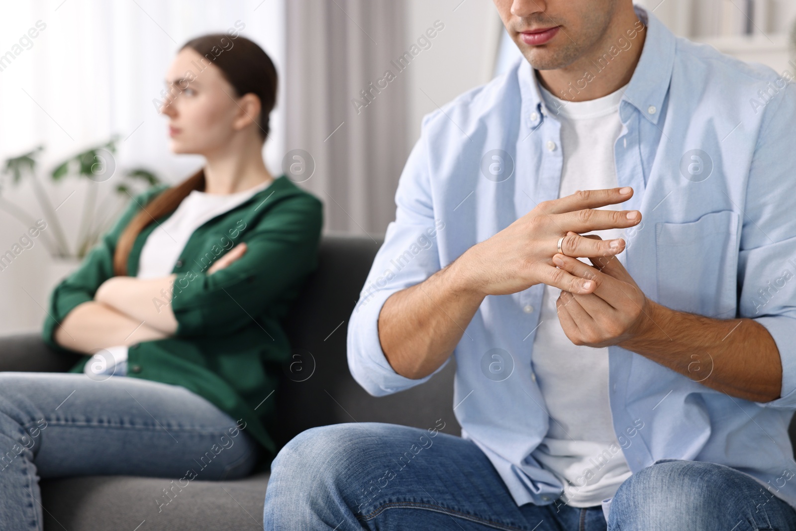 Photo of Man taking off engagement ring after quarrel with his wife at home, closeup