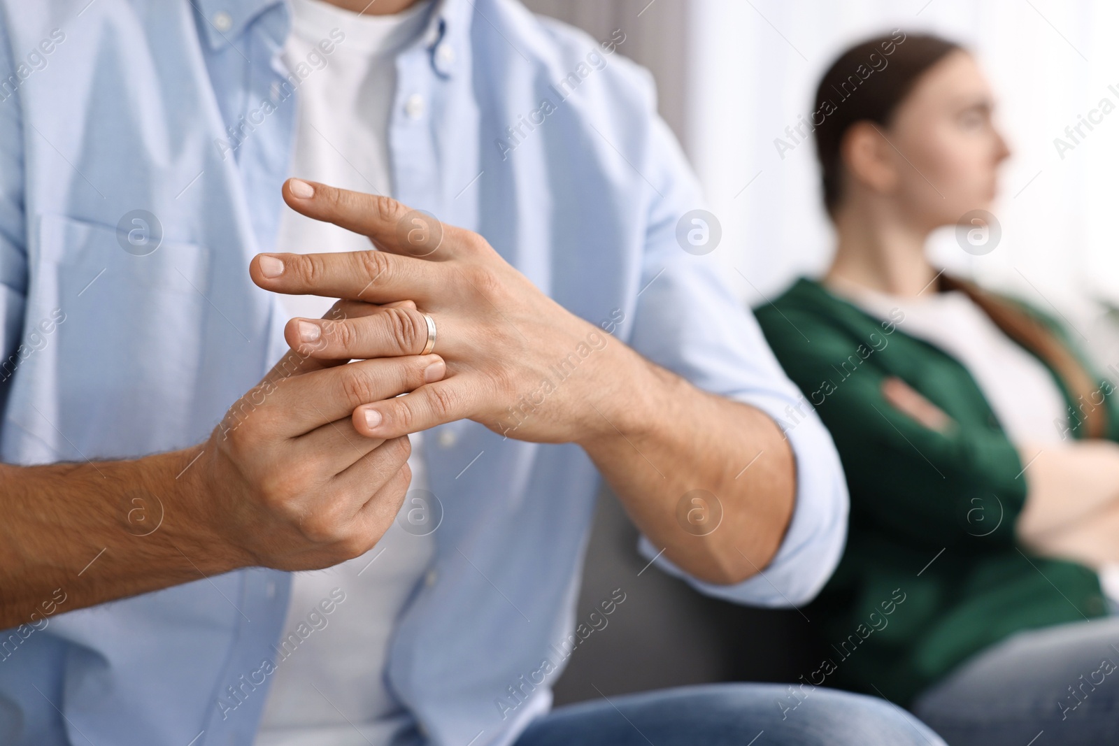 Photo of Man taking off engagement ring after quarrel with his wife at home, closeup