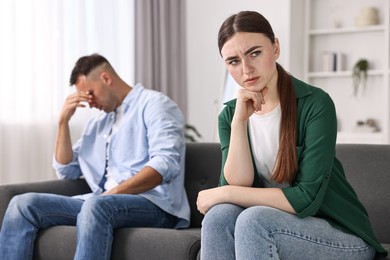 Upset woman ignoring her husband at home, selective focus