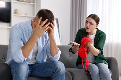 Photo of Wife showing mistress bra as proof to her unfaithful husband while he ignoring her at home