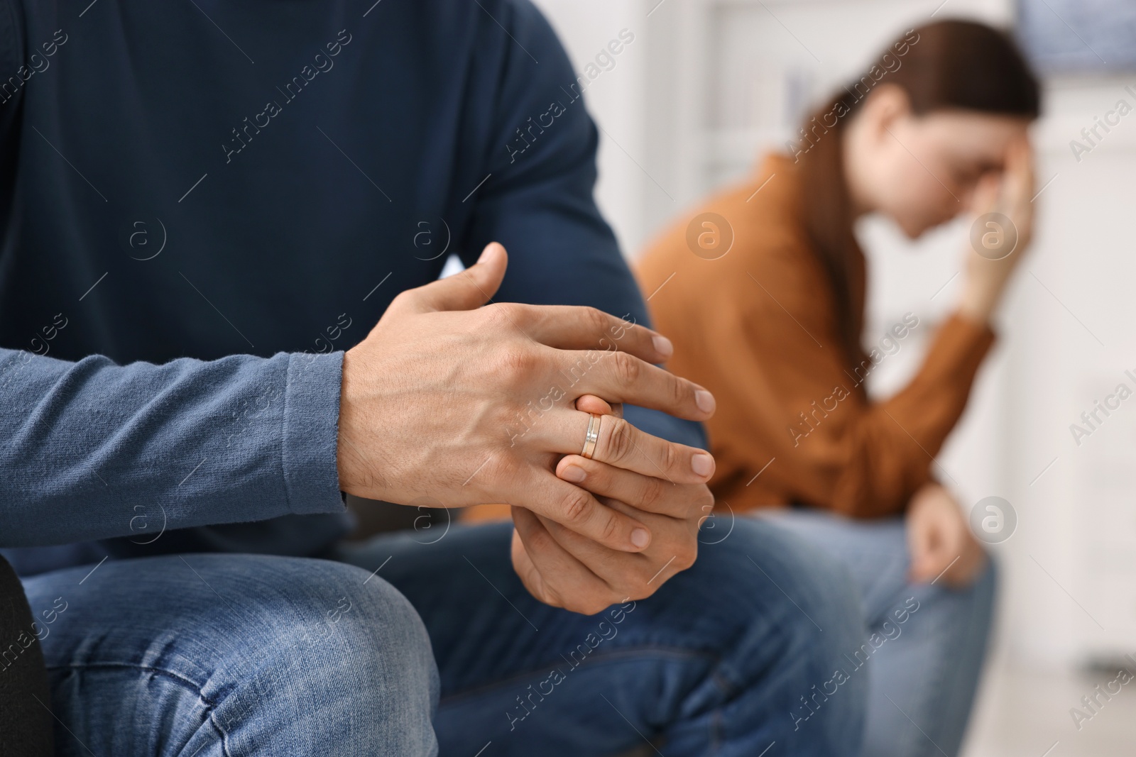 Photo of Man taking off engagement ring after quarrel with his wife at home, closeup