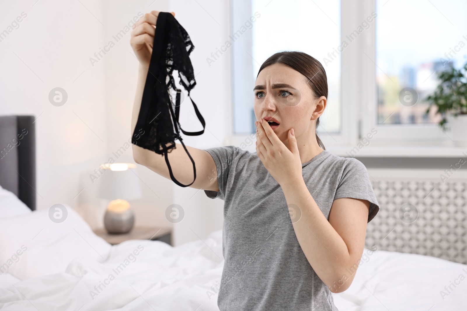 Photo of Surprised wife finding mistress bra in bedroom