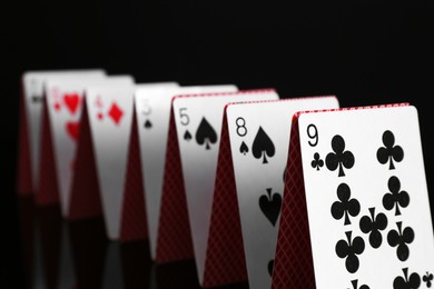 Photo of Row of playing cards on black background, closeup