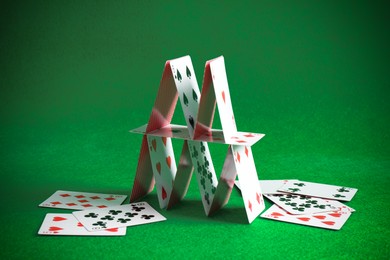 Photo of Collapsed house of playing cards on green background