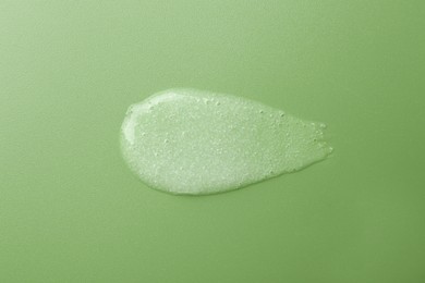 Photo of Smear of body scrub on green background, top view