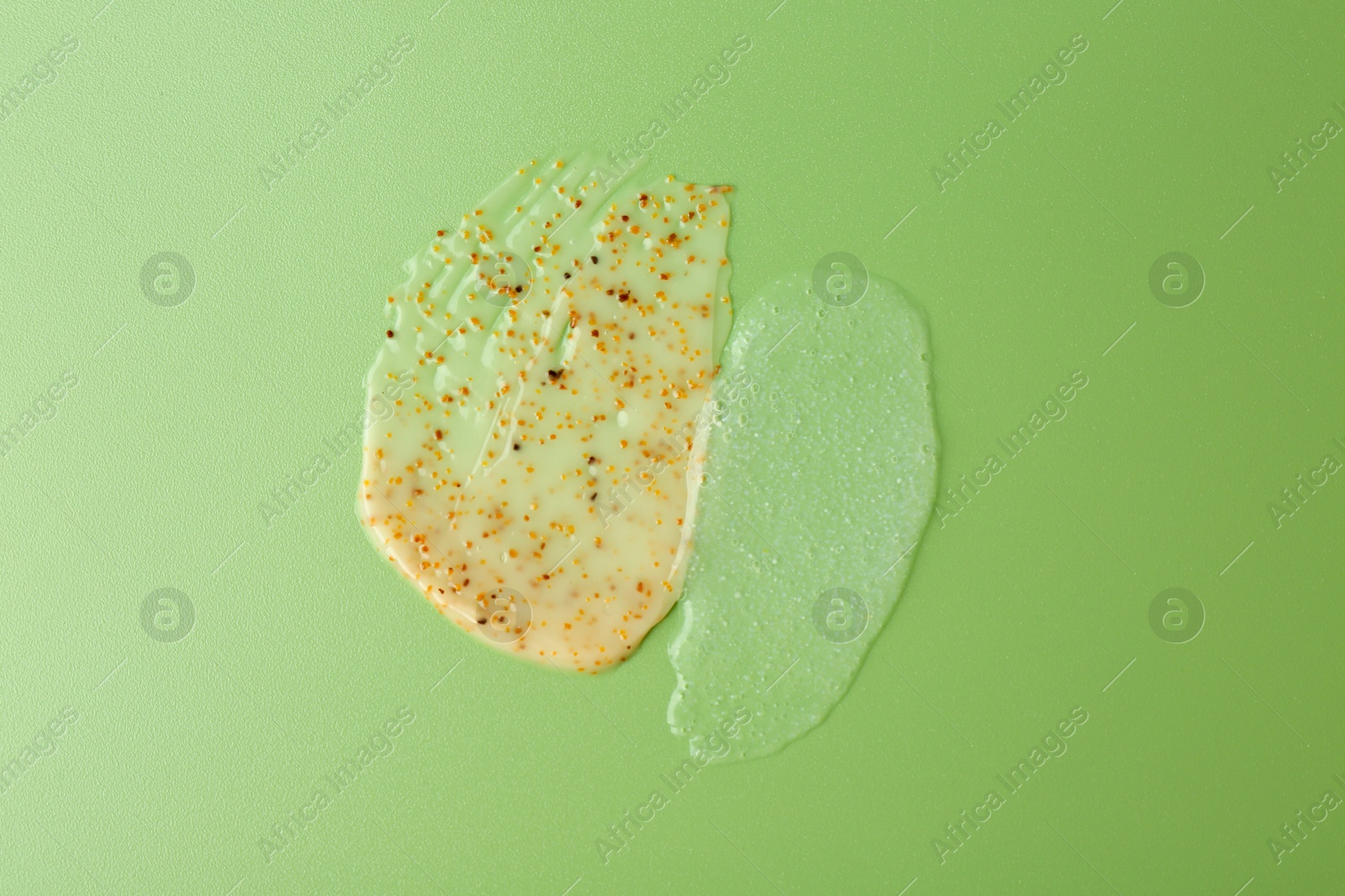 Photo of Smears of body scrubs on green background, top view