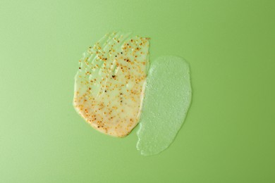 Photo of Smears of body scrubs on green background, top view