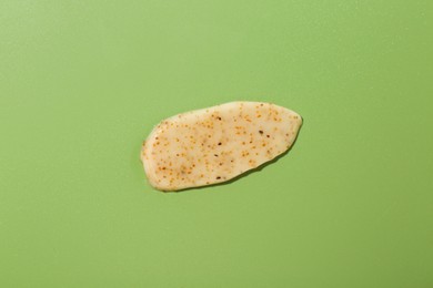 Photo of Smear of body scrub on green background, top view