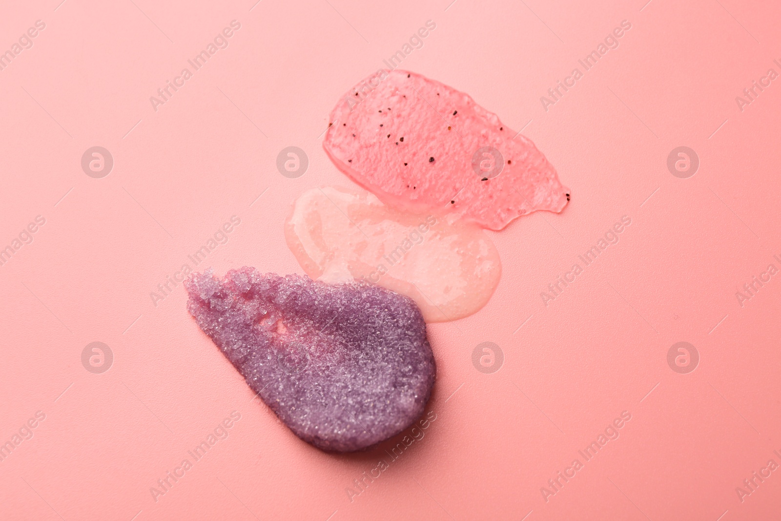 Photo of Smears of body scrubs on light pink background, top view