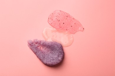 Photo of Smears of body scrubs on light pink background, top view