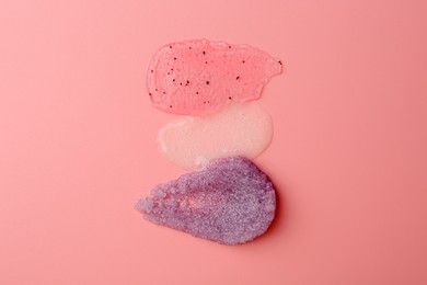 Photo of Smears of body scrubs on light pink background, top view