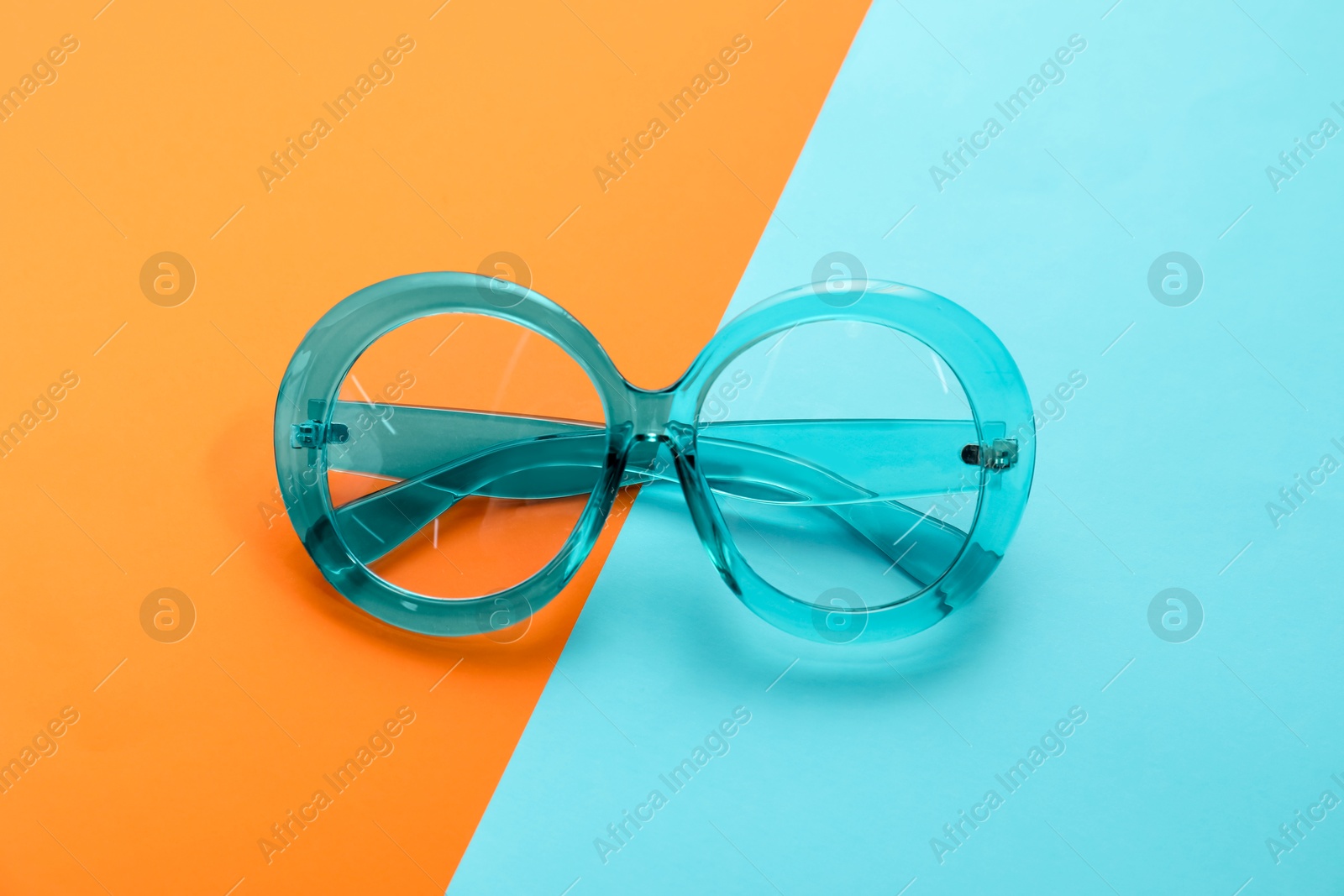 Photo of Stylish light blue glasses on color background