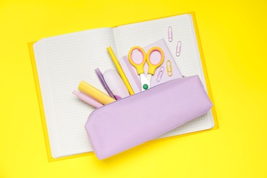 Photo of Pencil case and different stationery on yellow background, top view