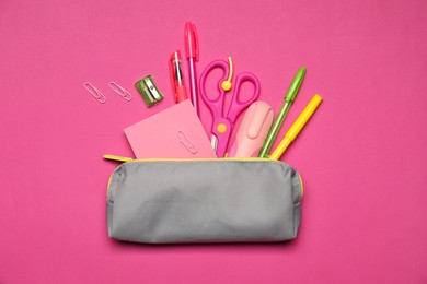 Photo of Pencil case and different stationery on pink background, flat lay