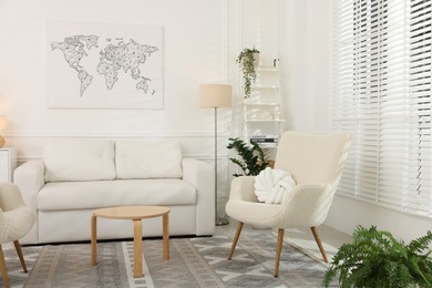 Photo of Soft armchairs, coffee table, sofa and green houseplants in living room