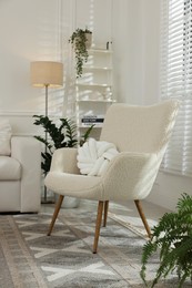 Photo of Soft armchair and green houseplants in living room