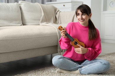 Photo of Happy woman playing ukulele on floor at home