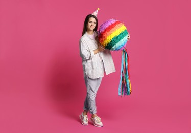 Photo of Woman with colorful pinata on pink background