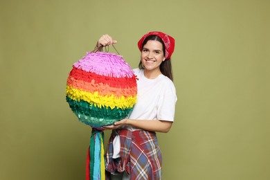 Happy woman with colorful pinata on green background