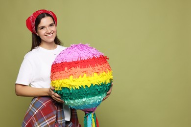 Photo of Happy woman with colorful pinata on green background, space for text