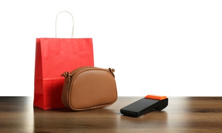 Photo of Payment terminal, purse and shopping bag on wooden table against white background