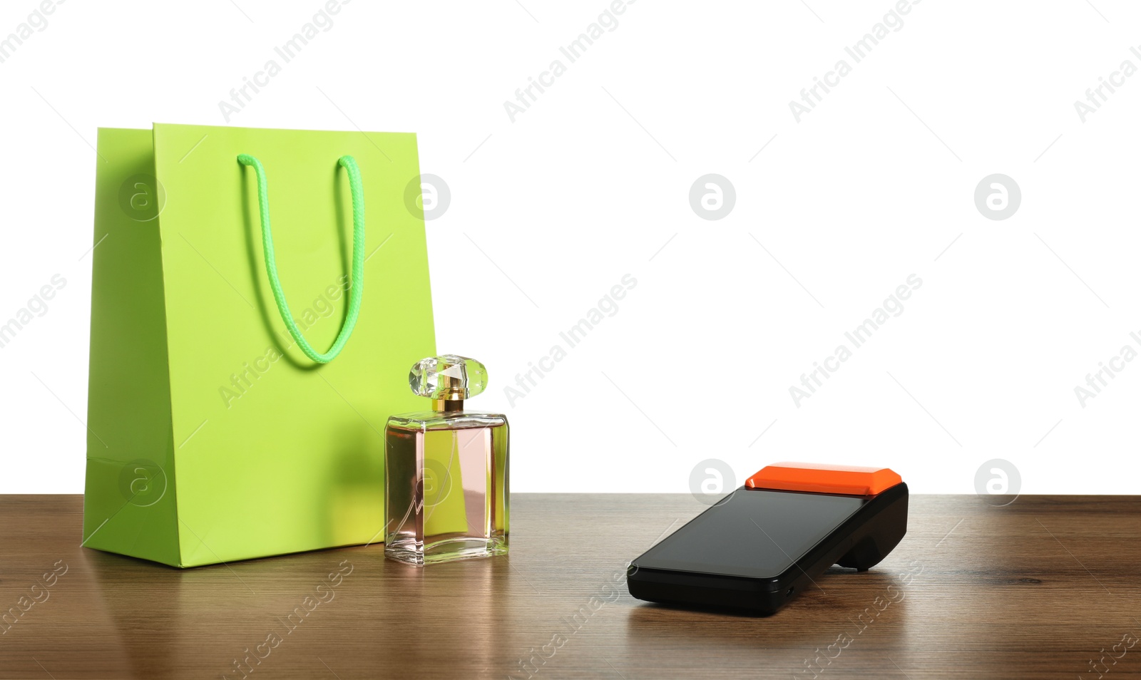 Photo of Payment terminal, perfume and shopping bag on wooden table against white background