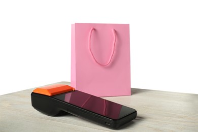 Photo of Payment terminal and shopping bag on wooden table against white background