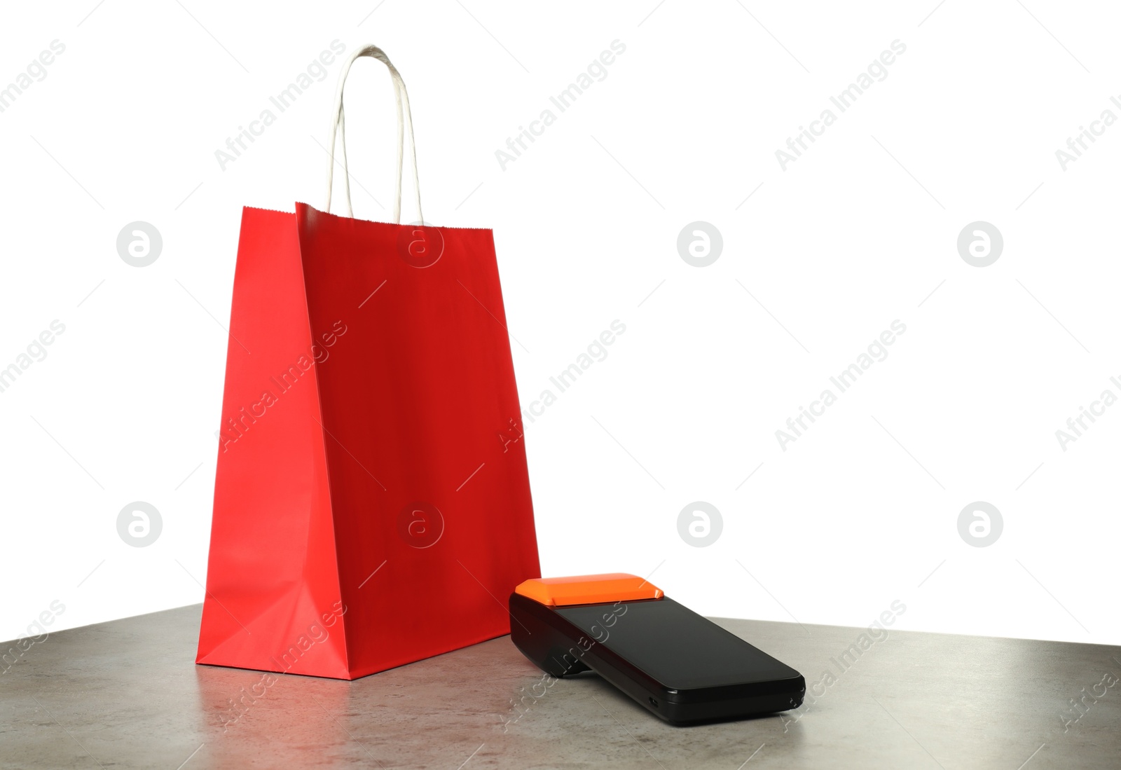 Photo of Payment terminal and shopping bag on grey table against white background