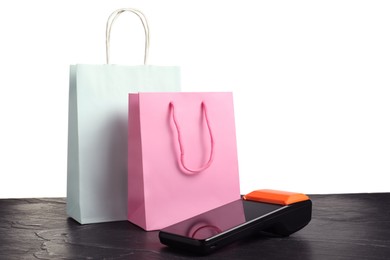 Photo of Payment terminal and shopping bags on black table against white background