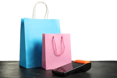 Photo of Payment terminal and shopping bags on black table against white background