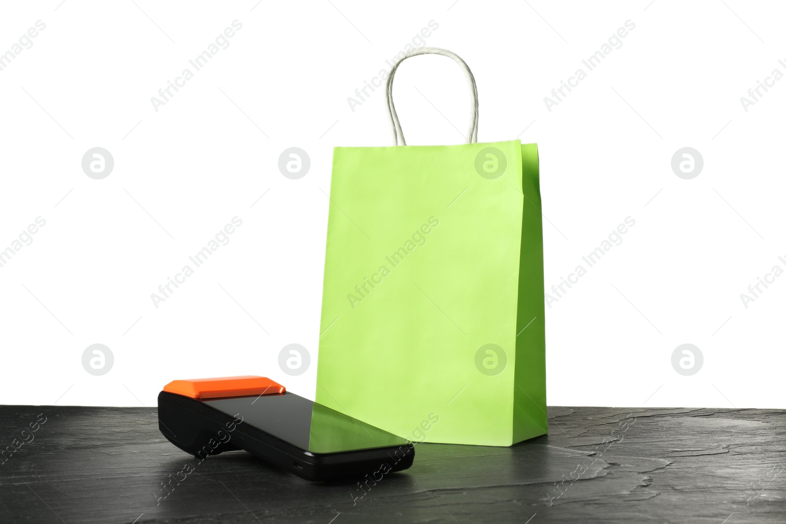 Photo of Payment terminal and shopping bag on black table against white background