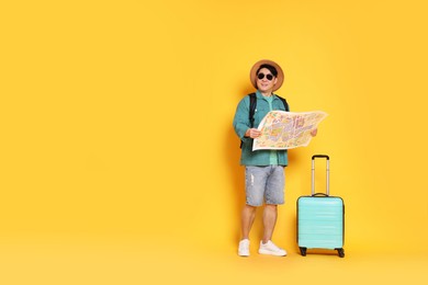 Photo of Traveller with map and suitcase on yellow background. Space for text