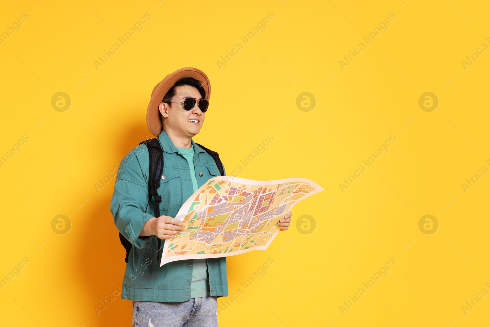 Photo of Traveller with map and backpack on yellow background. Space for text