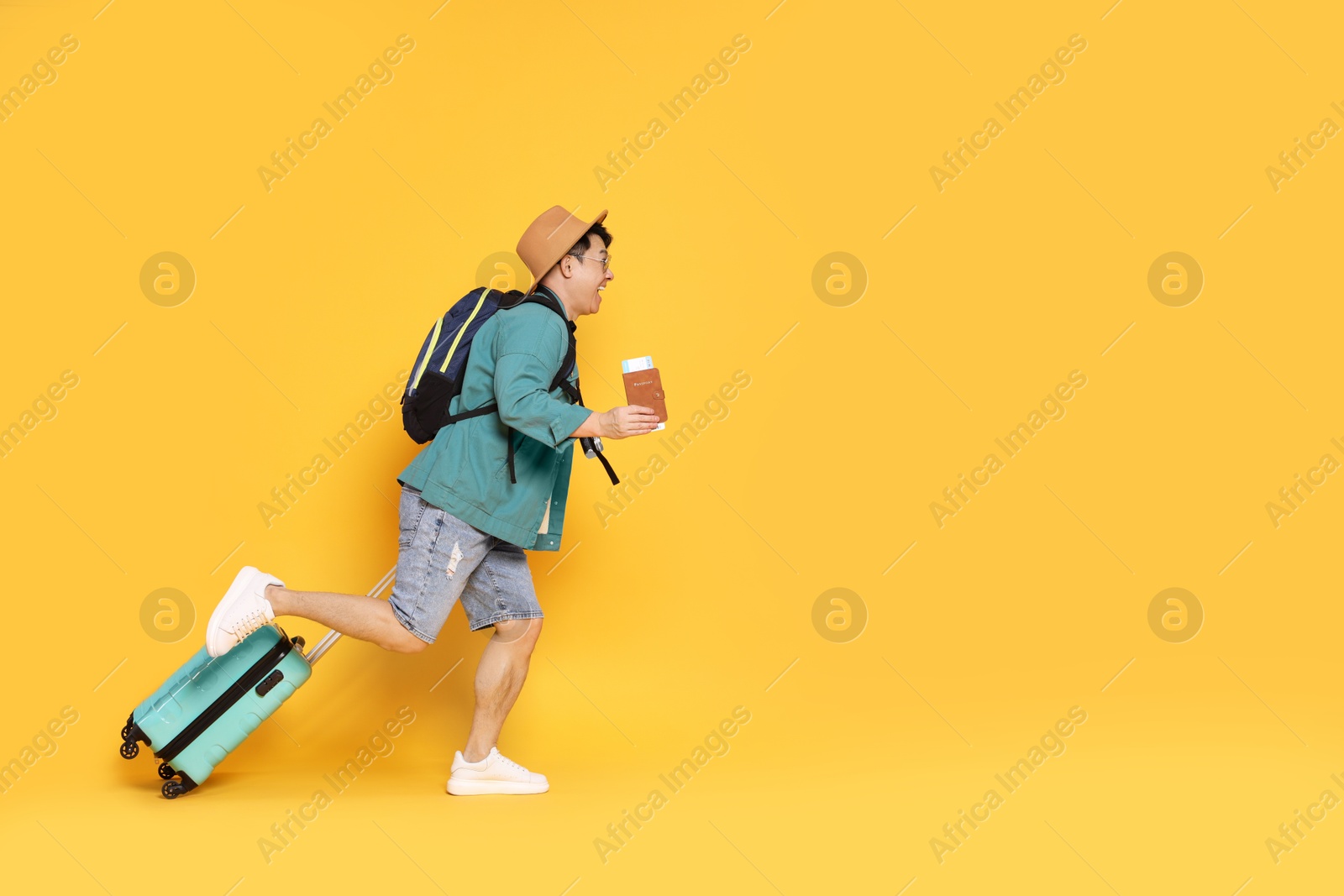 Photo of Traveller with passport and suitcase running on yellow background. Space for text