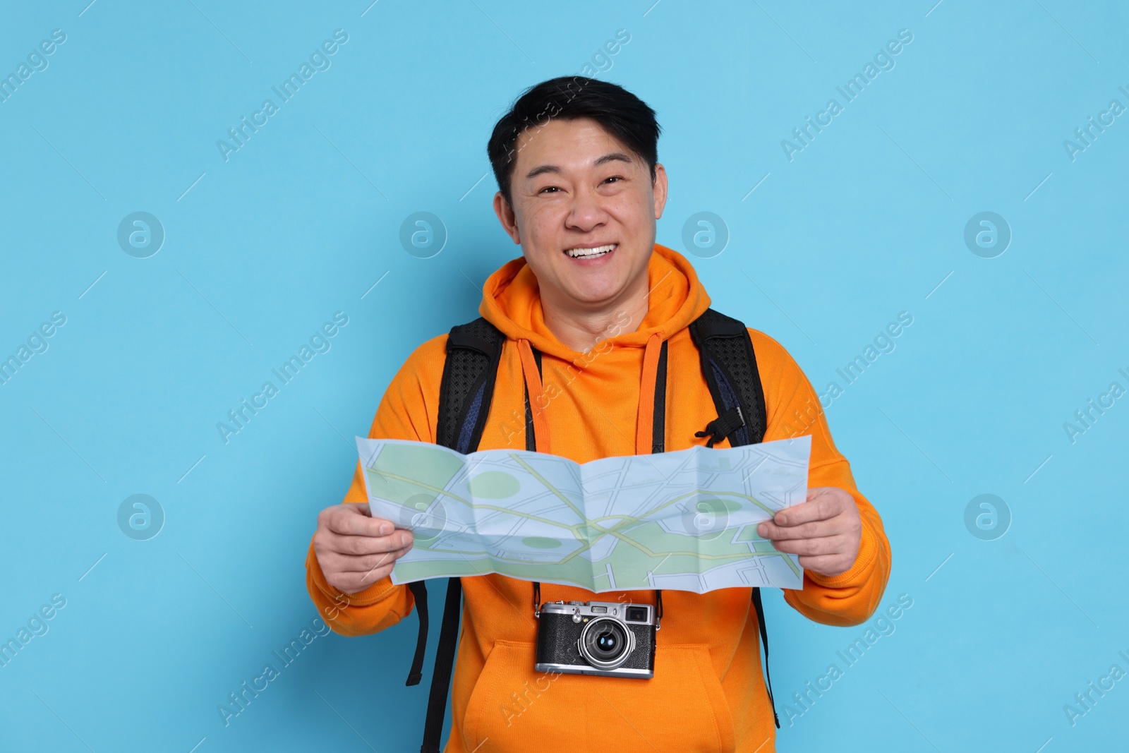 Photo of Happy traveller with map on light blue background